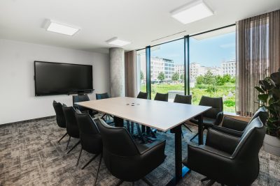 Stół konferencyjny i panoramiczne okna z widokiem na zieleń