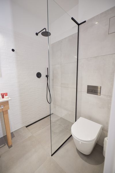 Prysznic walk-in z czarną armaturą i toaleta wisząca