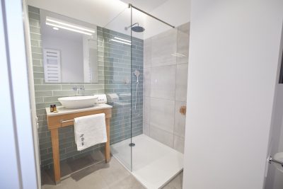 Łazienka z prysznicem walk-in wyłożonym zielonymi płytkami