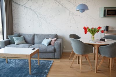 Salon z narożną sofą, stołem jadalnym i tapetą w gałęzie