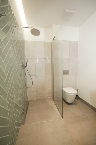 Prysznic walk-in wyłożony jasnozielonymi płytkami w jodełkę