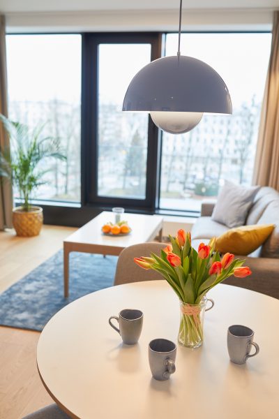 Stół z tulipanami i kubkami, w tle sofa przy oknie