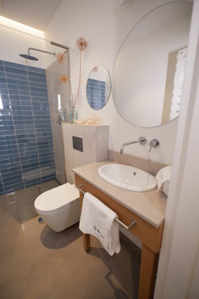 Łazienka z prysznicem walk-in, umywalką nablatową i okrągłym lustrem