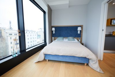 Druga sypialnia z niebieskim zagłówkiem przy narożnym oknie